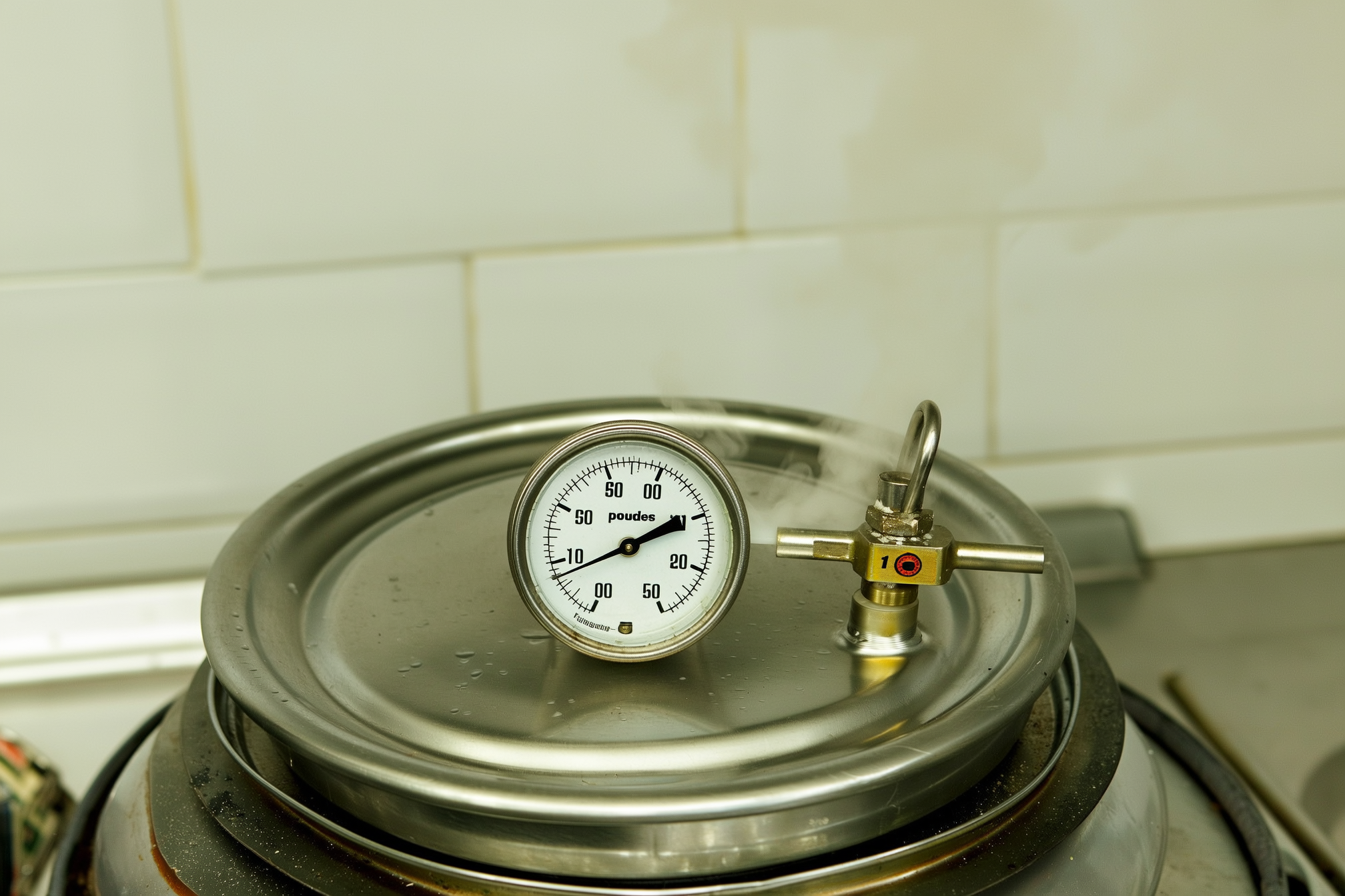 A pressure canner with the dial gauge reading 11 pounds, sitting on a stovetop with steam venting gently from the weighted petcock during potato processing